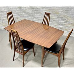 a wooden table with four chairs and a brick wall in the backgroung