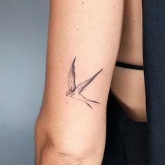 a small bird tattoo on the right arm and left arm is shown in black ink