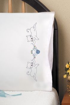 a pillow that has been embroidered onto the side of a bed with flowers on it