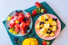 two plates filled with fruit on top of a blue cloth next to strawberries and watermelon