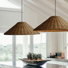 three hanging lights above a kitchen counter with pineapples in a bowl on it