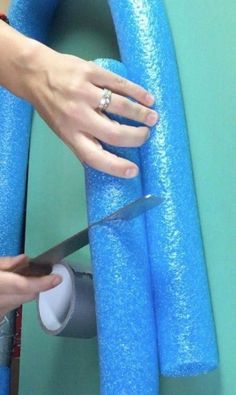 a person is using a pair of scissors to cut foam off the side of a blue tube