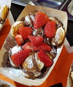 a box filled with pastries covered in chocolate and strawberries on top of an orange table