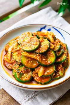 a white plate topped with zucchini and sauce on top of a wooden table