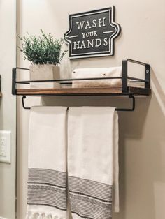 a towel rack with two white towels and a potted plant on top of it