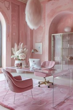 a room with pink walls, chairs and a desk in front of a large window