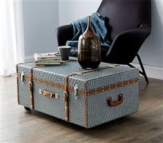 a blue suitcase sitting on top of a wooden floor next to a chair and coffee table