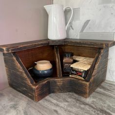 a wooden shelf with some books and a pitcher on it's side, next to a white vase