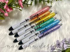 four pens with writing on them sitting next to flowers