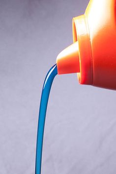 an orange and blue cup is pouring water into a red cup with a blue handle