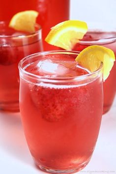 three glasses filled with red liquid and lemon wedges