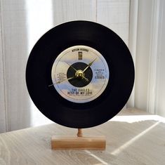 a black and white clock sitting on top of a wooden stand next to a window