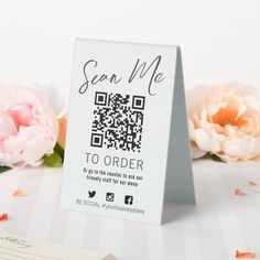 there is a card with a qr code on it next to some pink flowers