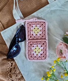 a pink crocheted bag sitting on top of a table next to sunglasses and flowers