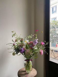 a vase filled with lots of flowers sitting on top of a table next to a window