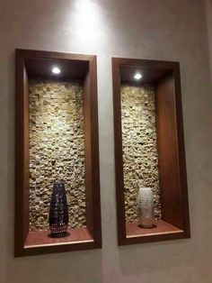 two vases sitting on display in front of stone wall panels with lights above them