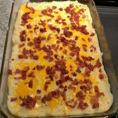 an uncooked casserole with cheese and bacon