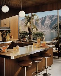 a kitchen with an island and bar stools in front of large windows overlooking mountains