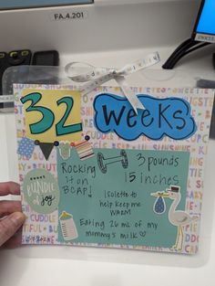 a hand holding up a sign that says 32 weeks