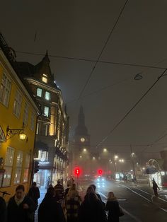 many people are walking down the street in the snow at night with their lights on