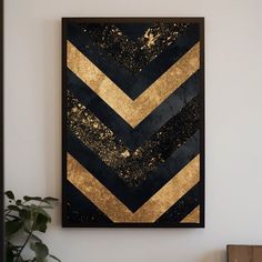 a black and gold framed art piece hanging on a wall next to a potted plant