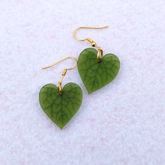 Simple heartleaf earrings. Green heart shaped earrings with engraved leaf veins. Shiny reflective studs that are half an inch and matte drop earrings hanging from a shiny gold leaf stud. These make a great low key Valentine's Day gift, especially if you don't like pink or red! Alternatively, they're for the plant lover in your life. The studs are also a nice unisex gift option. Choose the mini studs or the dangle earrings with default studs, fishhooks, huggies (leverbacks), or clip-ons. Dangle e