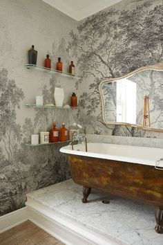 a bath tub sitting under a bathroom mirror next to a shelf with bottles on it