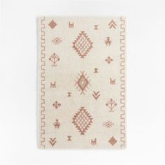 a white rug with red and brown designs on it, against a white wall background