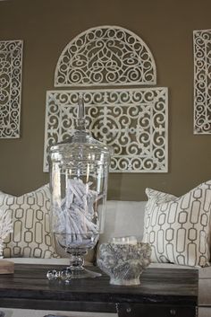 a table topped with two vases filled with water and surrounded by decorative wall art