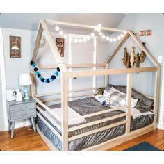 a child's bed made out of wood with lights strung from the top and bottom