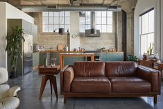 a brown leather couch sitting in a living room next to a wooden table and chairs