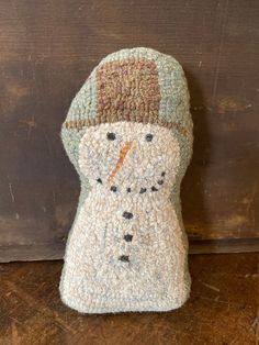 a crocheted snowman hat on top of a wooden table