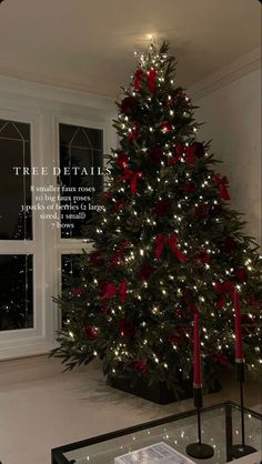 a christmas tree with red bows and lights in a living room next to a window