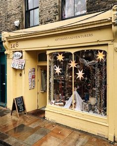 a yellow storefront with lots of windows and decorations on the side walk in front of it