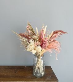 a vase filled with dried flowers on top of a wooden table