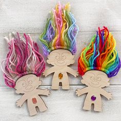 three wooden cutouts with different colored hair on them