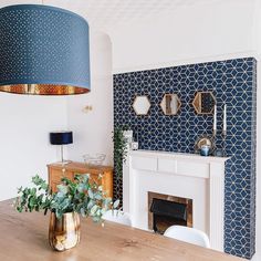 a living room with a fireplace and blue patterned wallpaper on the walls, along with a wooden dining table