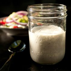 a glass jar filled with food sitting on top of a table next to a spoon