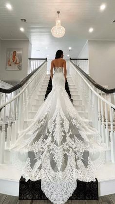 a woman in a white wedding dress standing on stairs with her back to the camera