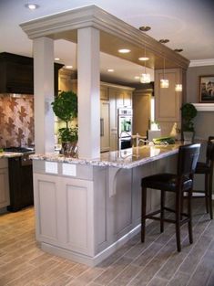 a large kitchen with an island in the middle and two bar stools at the end