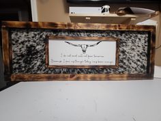 an animal print frame with a cow's skull on it and a quote in the middle