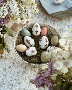 a bowl filled with eggs sitting on top of a table next to flowers and plates