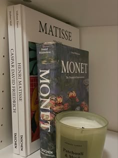 there is a candle next to two books on the shelf in front of each other