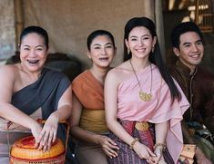 three women and one man are sitting on the ground with baskets in front of them