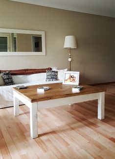 a living room with hard wood floors and a white table in the middle, surrounded by pillows