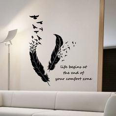 a living room with a white couch and black wall decal