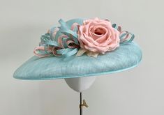 "A beautiful classic duck egg aqua blue wide brimmed sinamay straw hat with hints of pink.  This gorgeous headpiece is made using traditional straw sinamay, and has a combination of loops of the same straw in duck egg blue and the softest pale pink peach.  The loops continue around the entire crown of the hat, adding interest from all angles. Central to this design is an exquisite silk dupion rose in pale pink peach that sits just off centre, giving this headpiece a truly glamorous and elegant f Light Blue Hat For Royal Ascot Races, Blue Sinamay Hat For Summer, Light Blue Summer Hat For Races, Light Blue Summer Hats For Races, Blue Straw Hat For Spring, Blue Summer Hats With Handmade Flowers, Spring Wedding Turquoise Hats, Turquoise Hats For Spring Races, Turquoise Spring Racing Hat