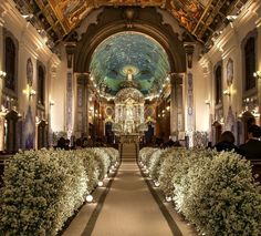 the inside of a church with many plants and flowers on either side of the aisle