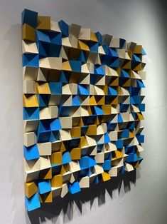 an abstract piece of art made out of cardboard boxes on a wall with white walls