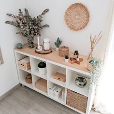 a white shelf with baskets and plants on it